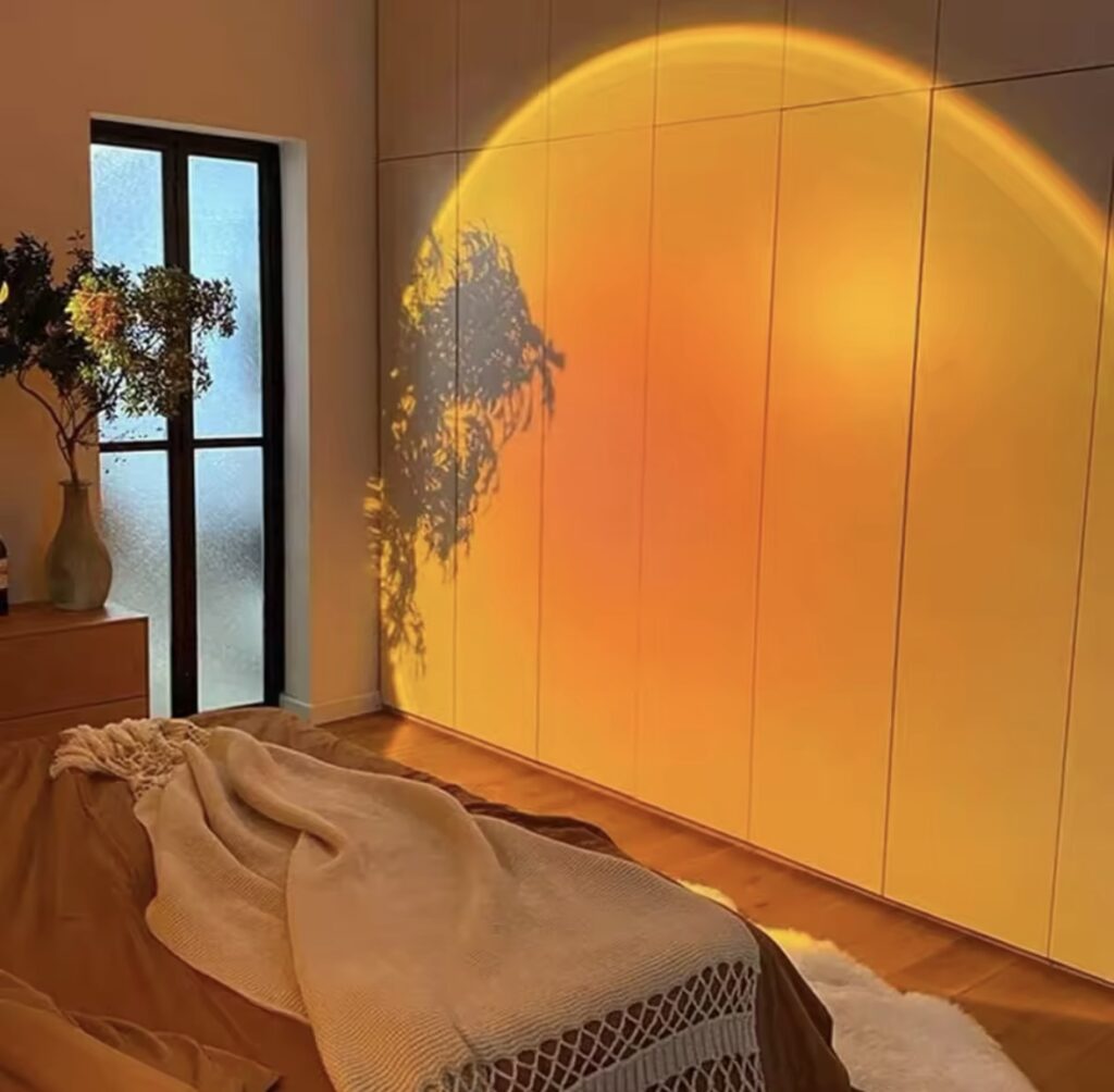 Sunset projection lamp casting a golden glow across a bedroom wall